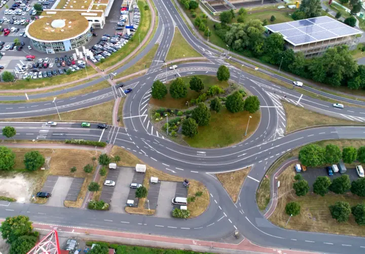 Vista aérea de una rotonda con tráfico, rodeada de edificios y aparcamientos. Un lugar ideal en una autopista donde puede realizar un cambio de sentido.
