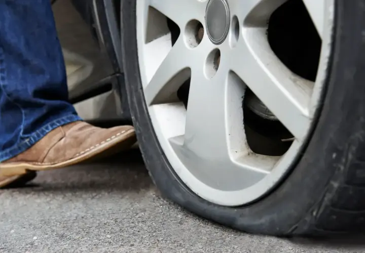 Un neumático runflat pinchado, con un pie saliendo del coche.