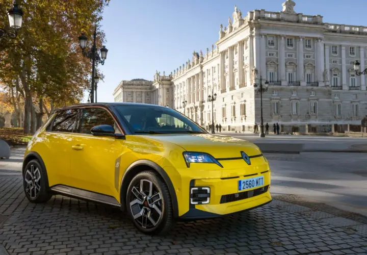 Coche amarillo con etiqueta ECO, aparcado frente a un edificio histórico. Los coches con etiqueta eco pagan impuesto de circulación, pero este parece disfrutar de un día soleado.