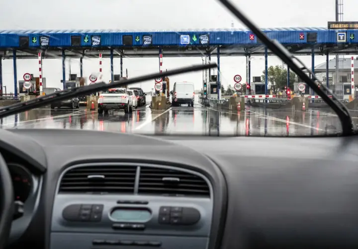 Fila de coches en un día lluvioso en los peajes de España. El coche se acerca a las cabinas de pago.