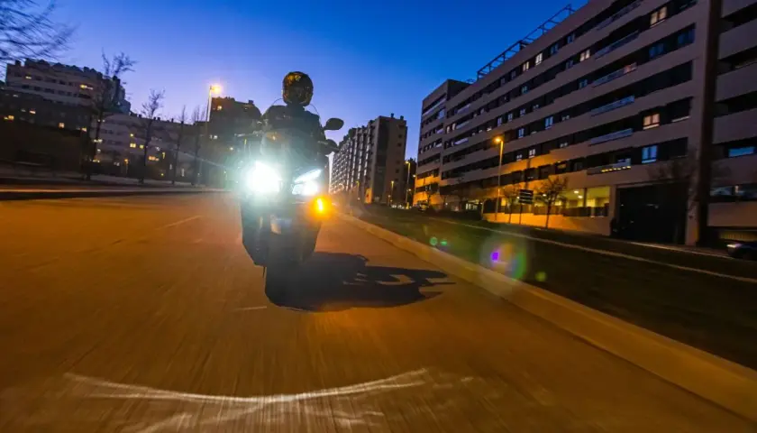 Motociclista con luces potentes de noche. Para no deslumbrar, es importante ajustar la altura de los faros y usar luces de baja intensidad cuando sea posible.