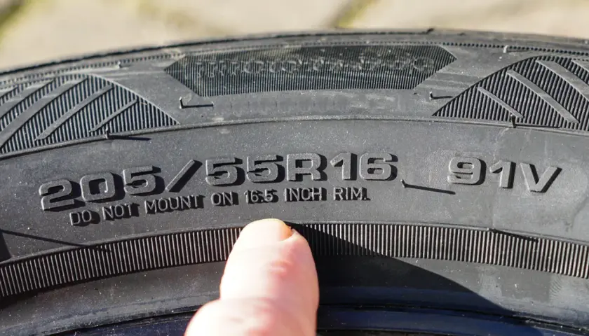 Dedo señala inscripción en neumático: 205/55R16 91V. ¡Cuidado con la caducidad neumáticos!