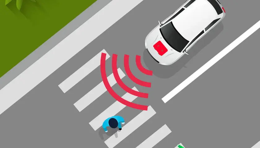 Coche eléctrico blanco se acerca a un paso de peatones. El sonido de los coches eléctricos es casi inaudible, pero las ondas rojas indican su presencia.