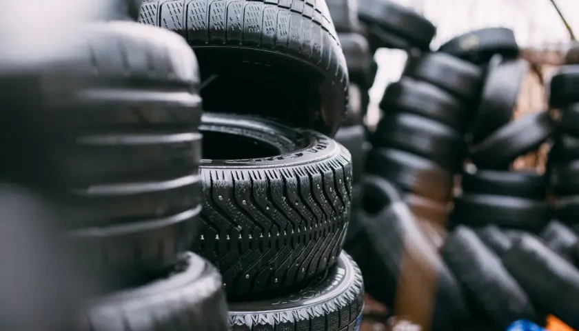 Montón de neumáticos mojados apilados. ¿Cuánto pesa un neumático? La imagen muestra una pila de neumáticos de coche, algunos con clavos para el invierno.