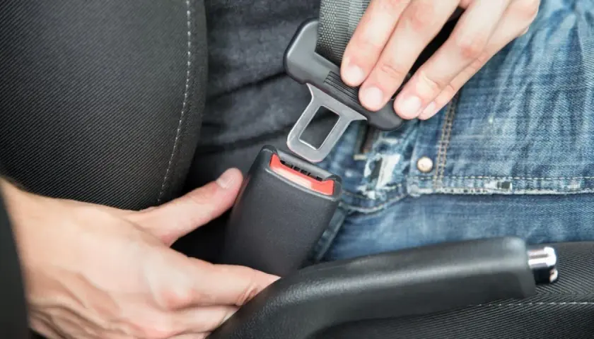 Persona abrochando el cinturón de seguridad en un coche. En un turismo es obligatorio utilizar los cinturones de seguridad.