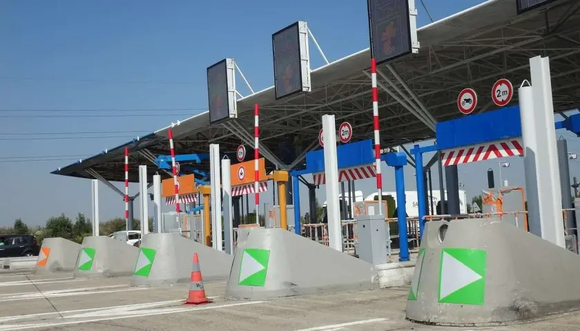 Peaje de autopista con carriles de pago y señalización. Así como funciona vía T, con barreras y luces indicadoras.