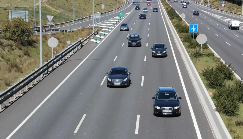 En el carril de entrada, ¿cómo debe circular? Un coche negro circula por el carril de entrada de una autopista, con otros vehículos delante y detrás.