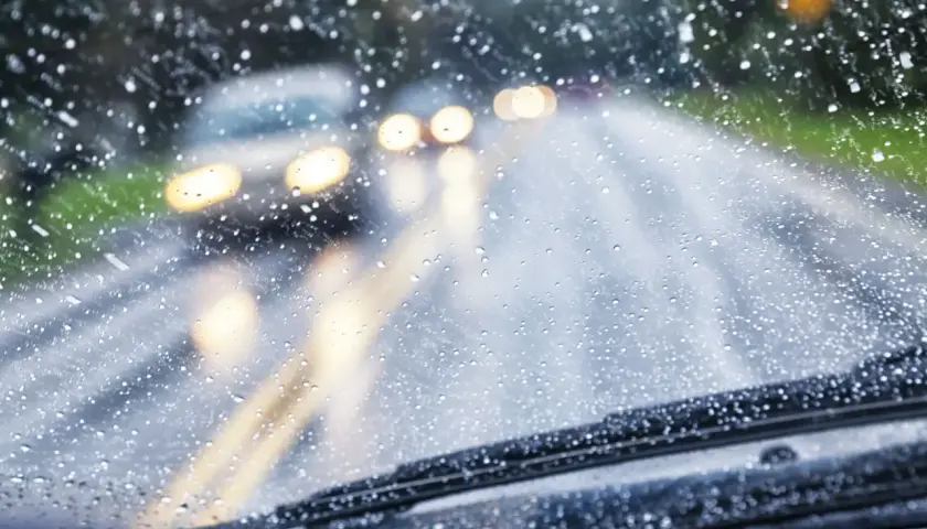Si conduciendo le sorprende una lluvia torrencial, el parabrisas se llena de gotas. Luces de otros coches se difuminan en la carretera mojada.
