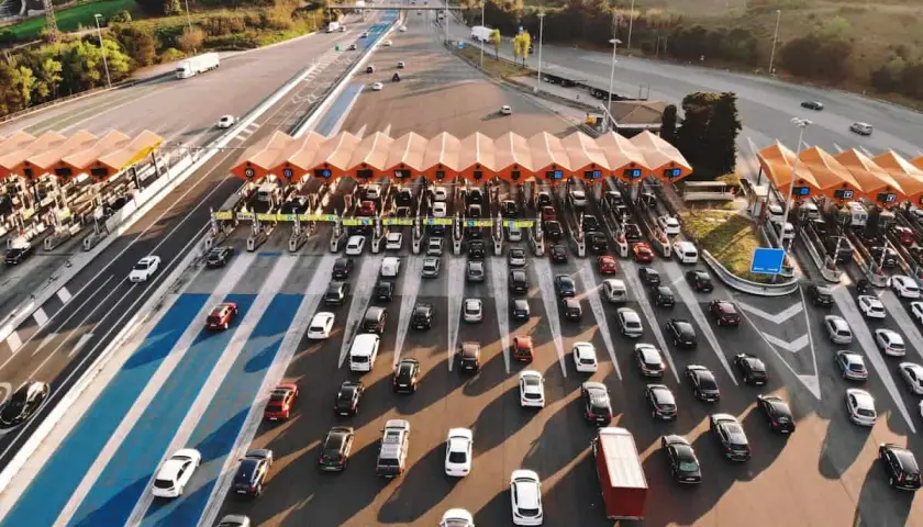 Larga fila de coches en un peaje, creando un gran atasco. Los vehículos esperan pacientemente su turno para pasar.