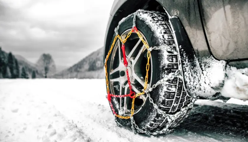Rueda de coche con cadenas para garantizar la viabilidad invernal en un paisaje nevado.