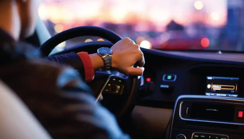 Persona conduce de noche en EE.UU., atento al **límite de velocidad** y al tráfico urbano.