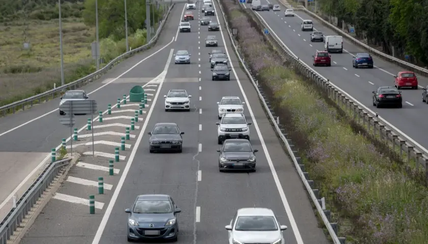 Tráfico en autopista, coches circulando. ¿Cuánto vale el peaje de Madrid? La carretera se ve con vegetación a los lados.