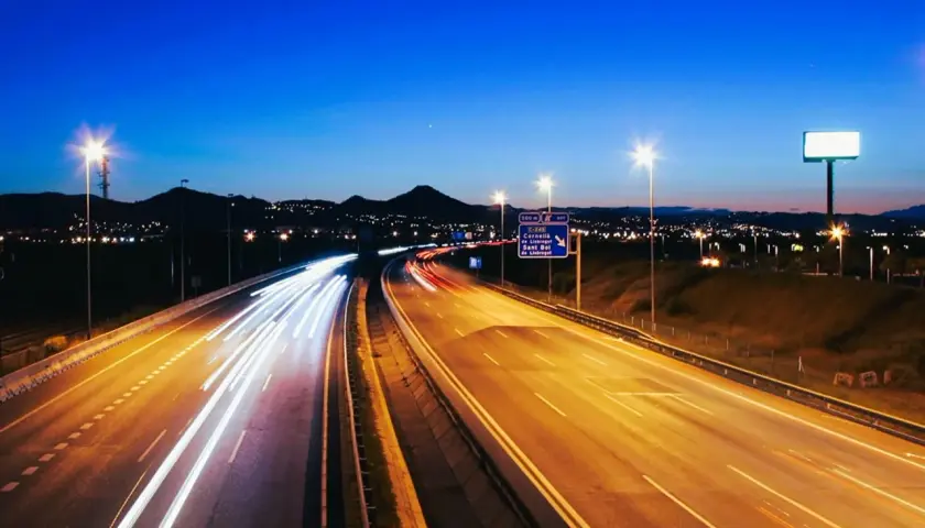 Autopista nocturna con estelas de luz de vehículos, reflejando la **estrategia seguridad vial 2030** para un futuro más seguro.