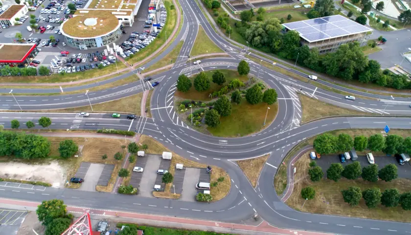 Vista aérea de una rotonda con tráfico, rodeada de edificios y aparcamientos. Un lugar ideal en una autopista donde puede realizar un cambio de sentido.