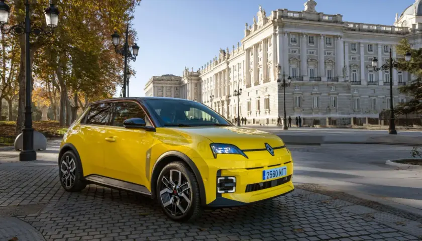 Coche amarillo con etiqueta ECO, aparcado frente a un edificio histórico. Los coches con etiqueta eco pagan impuesto de circulación, pero este parece disfrutar de un día soleado.