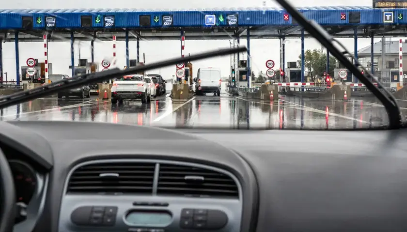 Fila de coches en un día lluvioso en los peajes de España. El coche se acerca a las cabinas de pago.