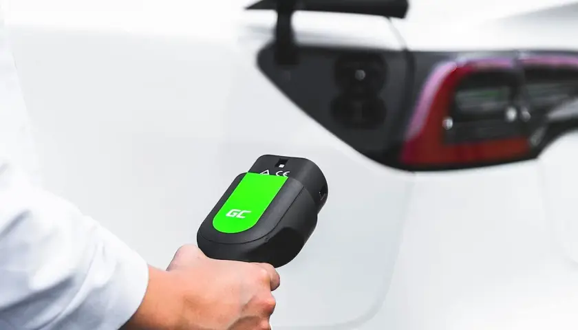 Mano sujetando un cargador de coche eléctrico, listo para conectar. Averigua cuanto cuesta cargar un coche eléctrico en Carrefour.