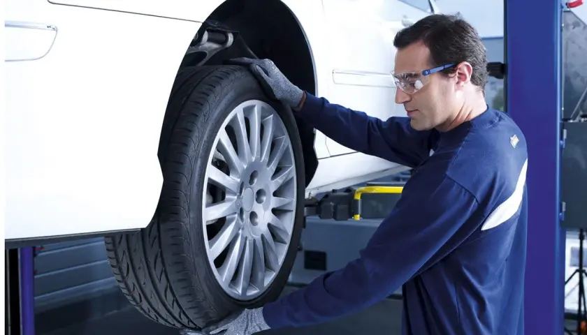 Mecánico revisa un neumático para vulcanizar pinchazo lateral.
