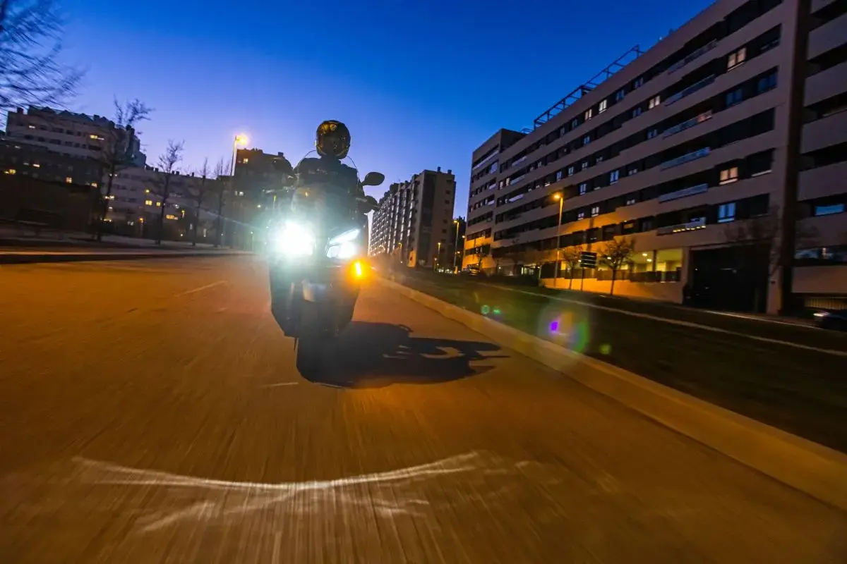 Motociclista con luces potentes de noche. Para no deslumbrar, es importante ajustar la altura de los faros y usar luces de baja intensidad cuando sea posible.