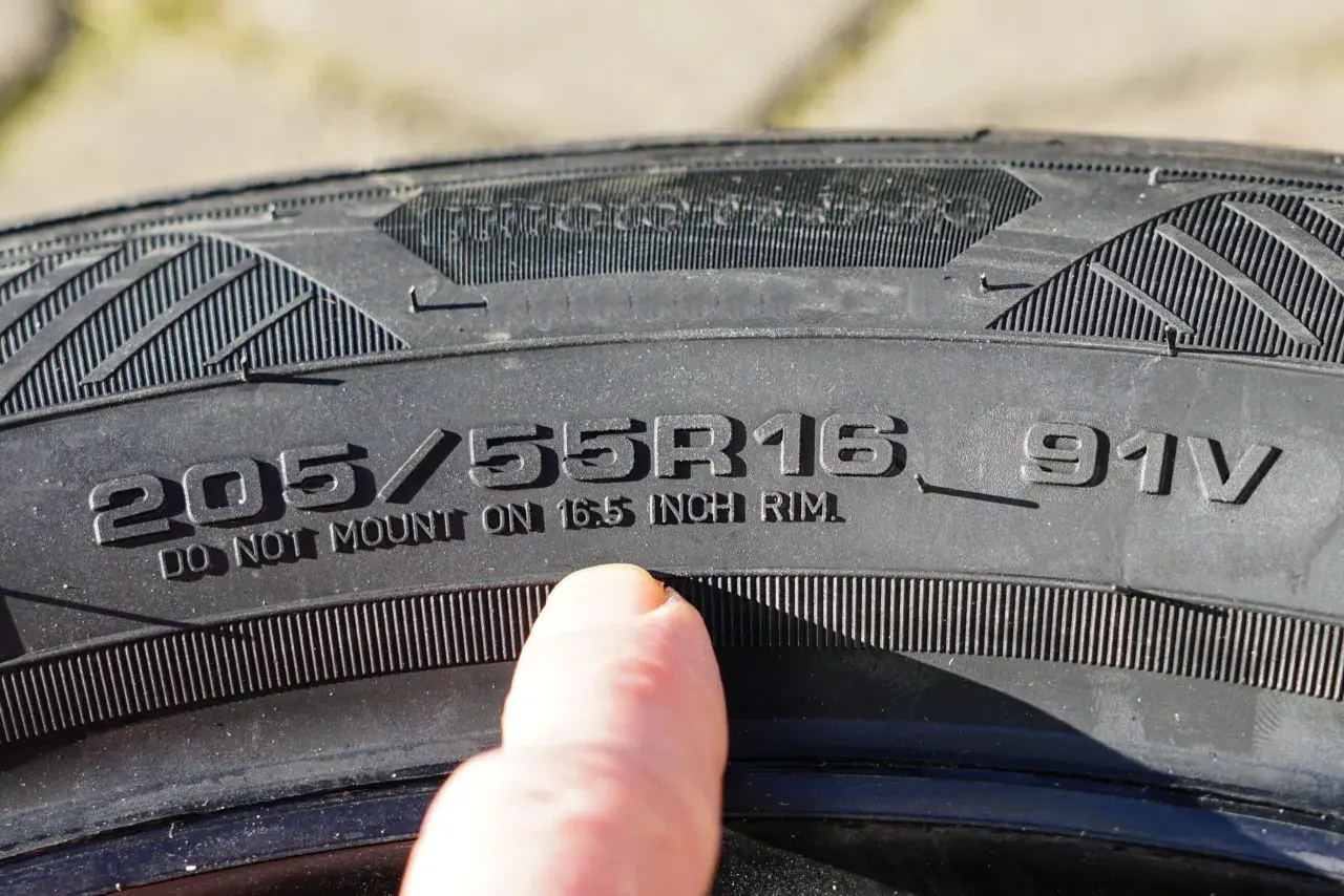 Dedo señala inscripción en neumático: 205/55R16 91V. ¡Cuidado con la caducidad neumáticos!