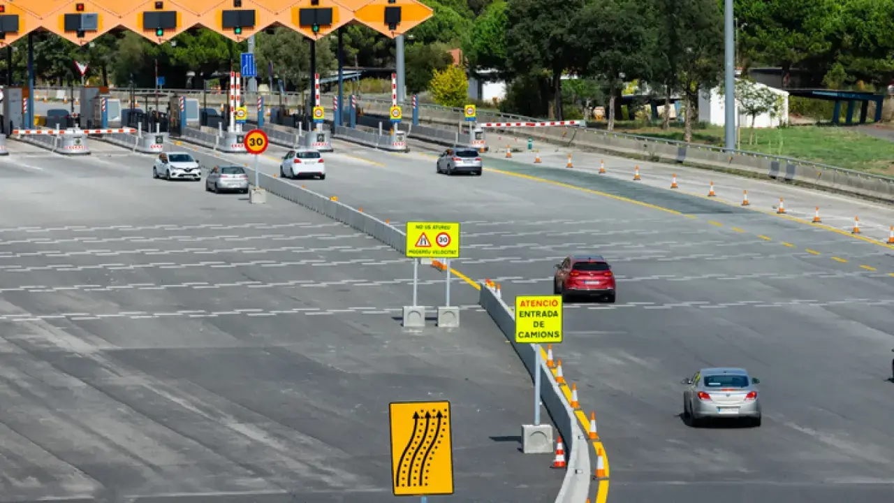 Peaje con carriles de pago y señales de tráfico. El ap-66 precio es visible en una señal.