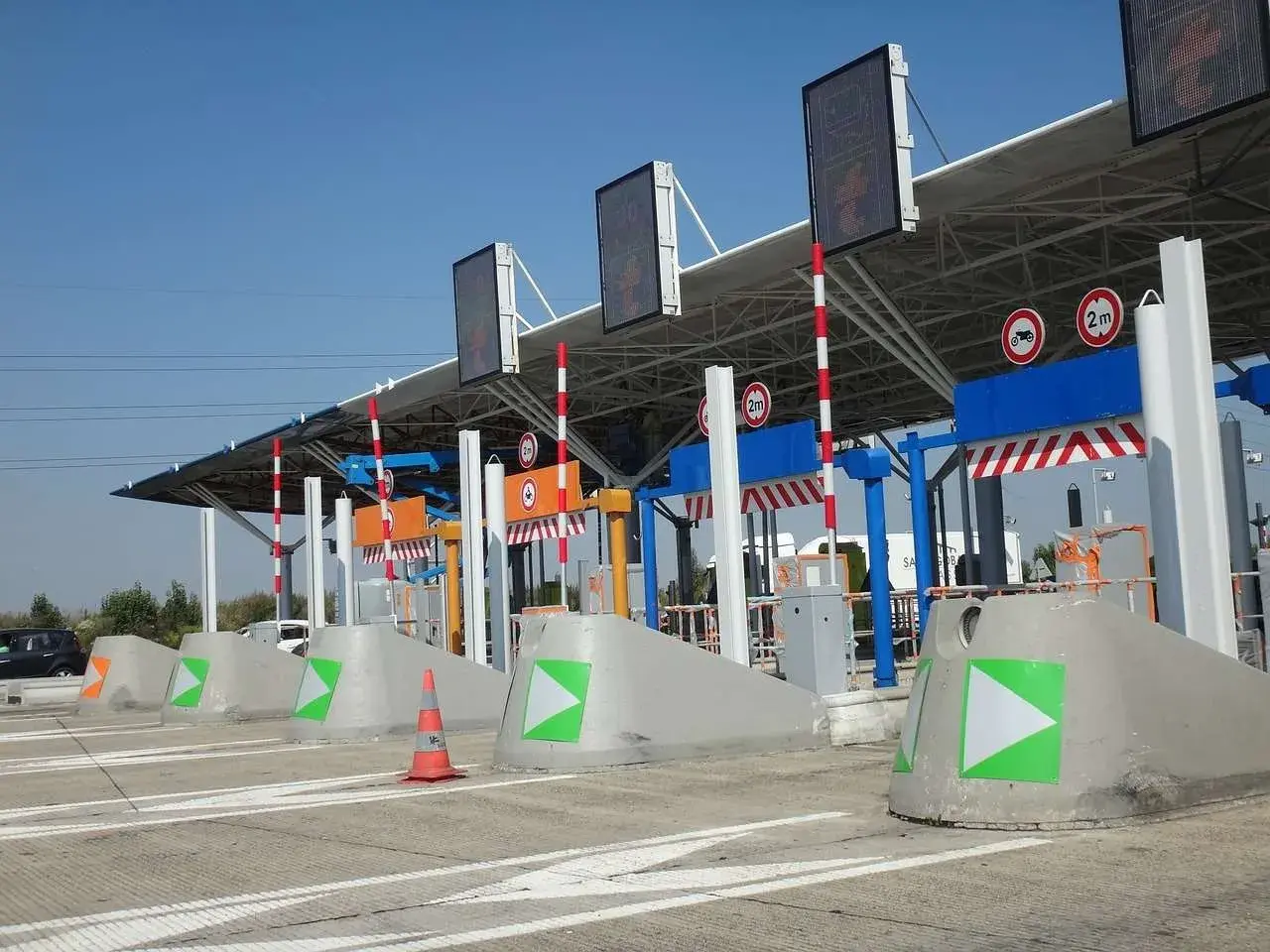 Peaje de autopista con carriles de pago y señalización. Así como funciona vía T, con barreras y luces indicadoras.
