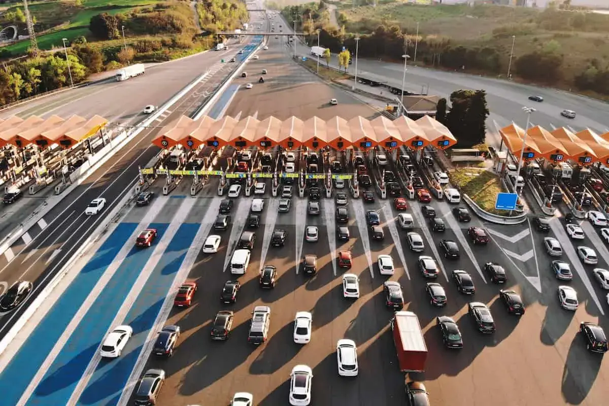 Larga fila de coches en un peaje, creando un gran atasco. Los vehículos esperan pacientemente su turno para pasar.