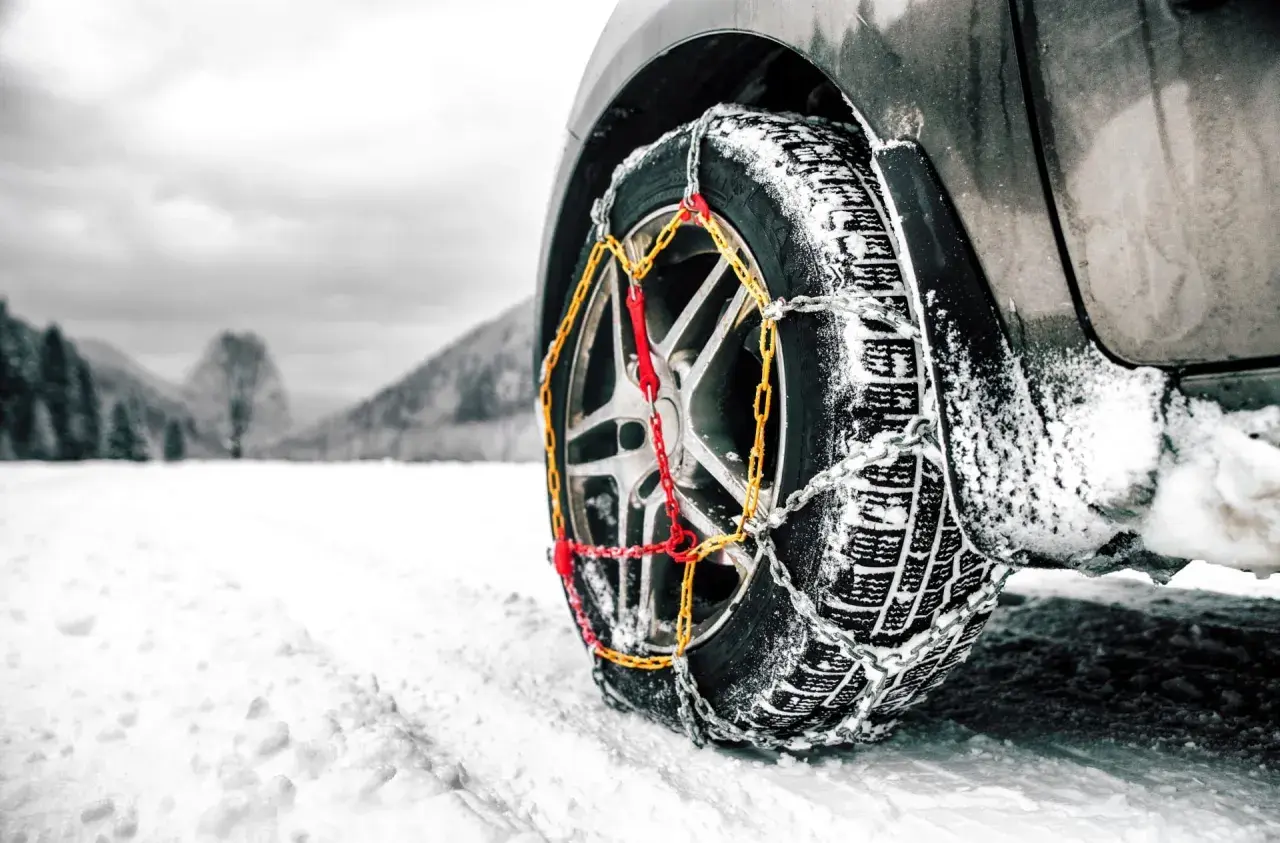 Rueda de coche con cadenas para garantizar la viabilidad invernal en un paisaje nevado.