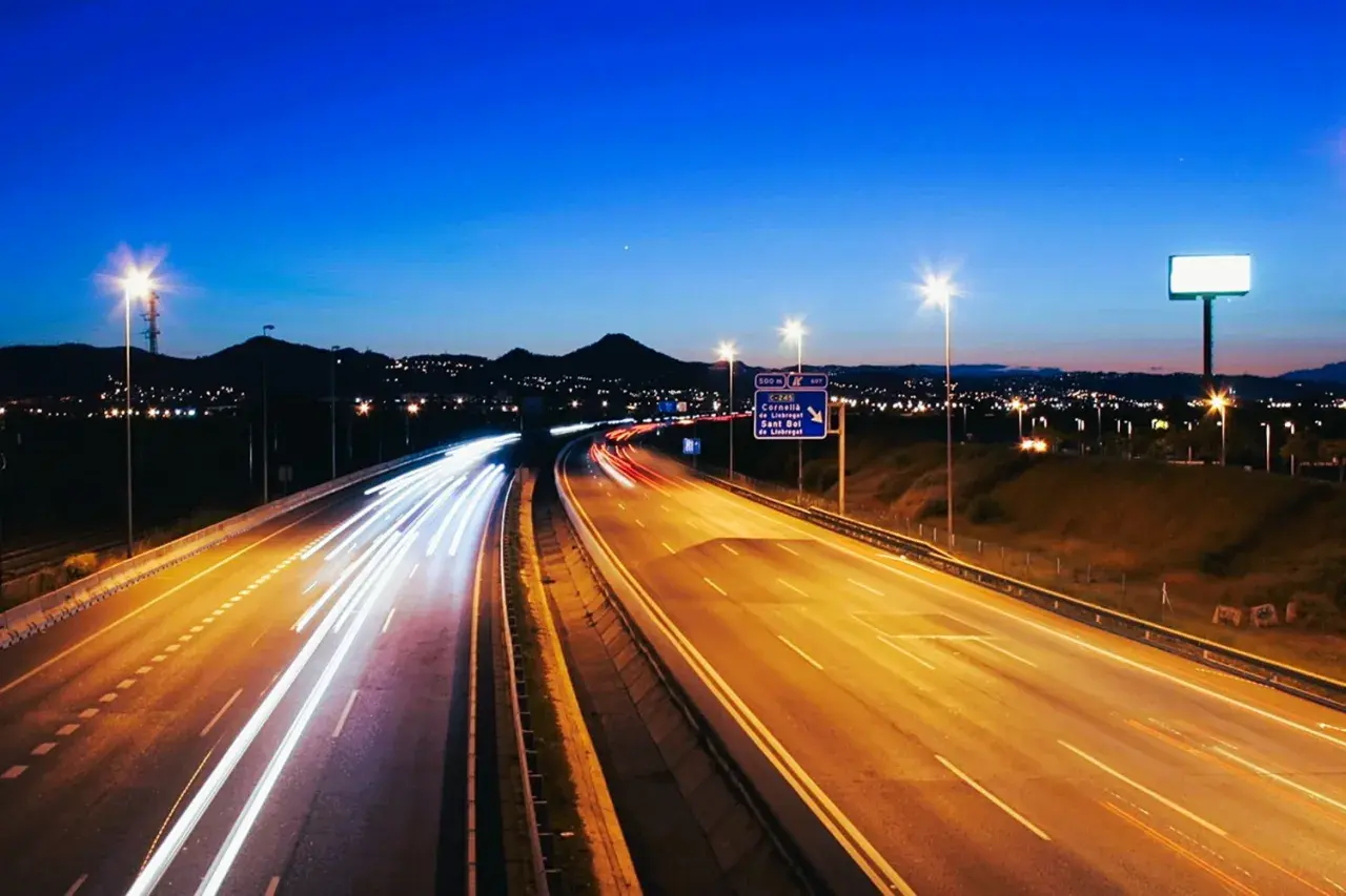 Autopista nocturna con estelas de luz de vehículos, reflejando la **estrategia seguridad vial 2030** para un futuro más seguro.