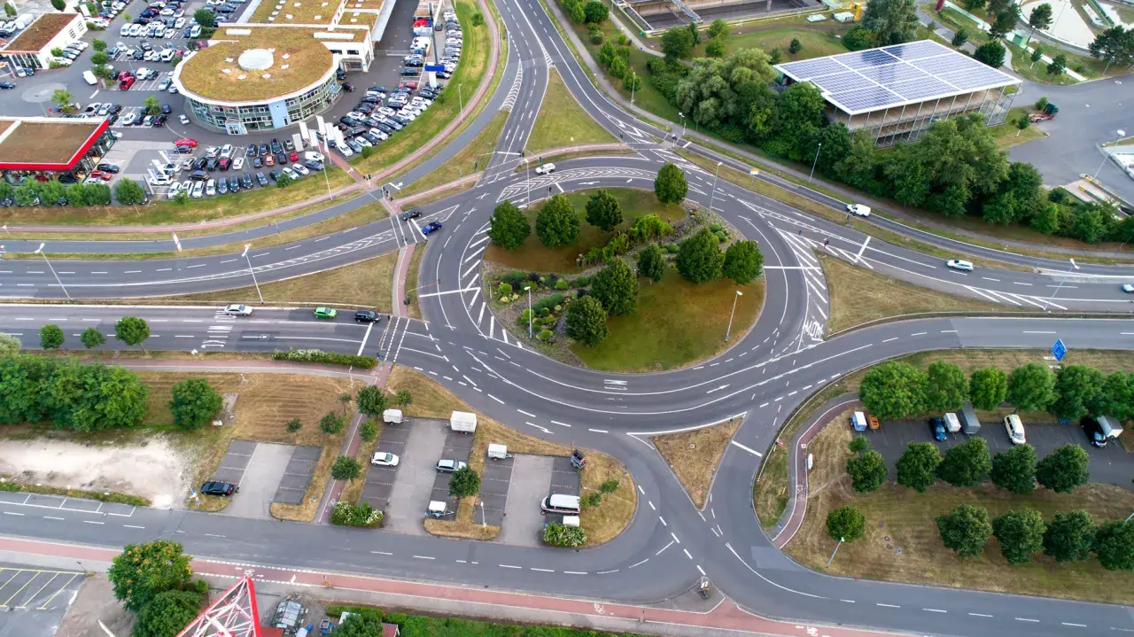 Vista aérea de una rotonda con tráfico, rodeada de edificios y aparcamientos. Un lugar ideal en una autopista donde puede realizar un cambio de sentido.