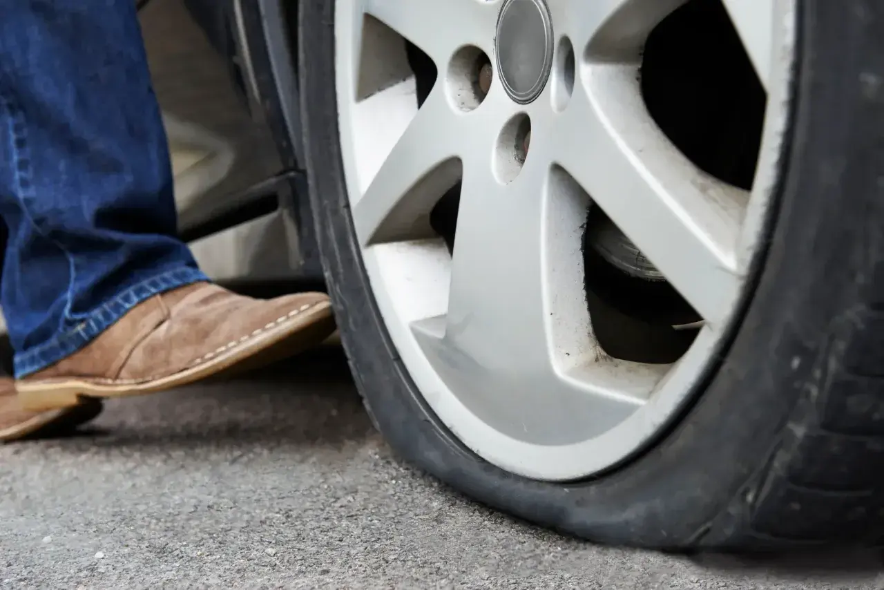 Un neumático runflat pinchado, con un pie saliendo del coche.