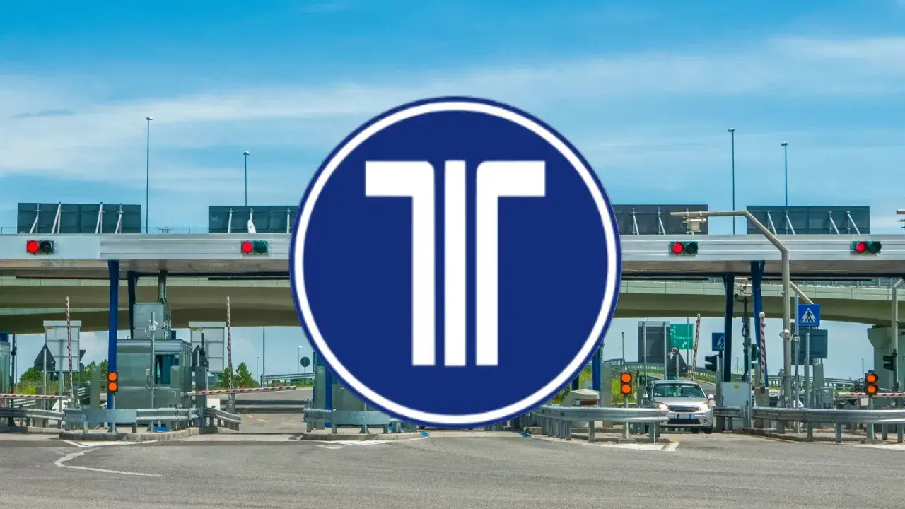 Peaje con señal azul y blanca de "T". Un coche se acerca a pagar con su tarjeta peajes.