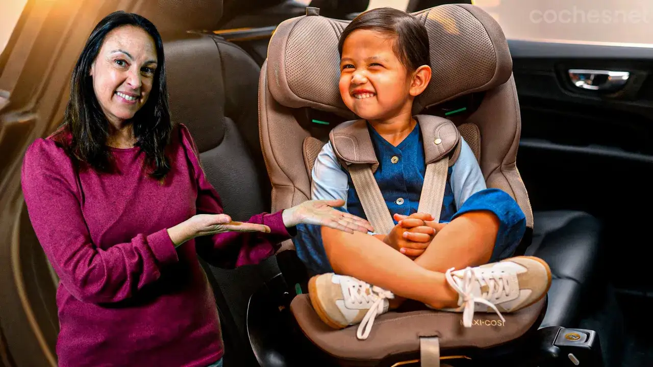 Una mujer sonr&iacute;e mientras se&ntilde;ala a un ni&ntilde;o feliz sentado en su silla de coche. Los ni&ntilde;os en el coche viajan seguros.