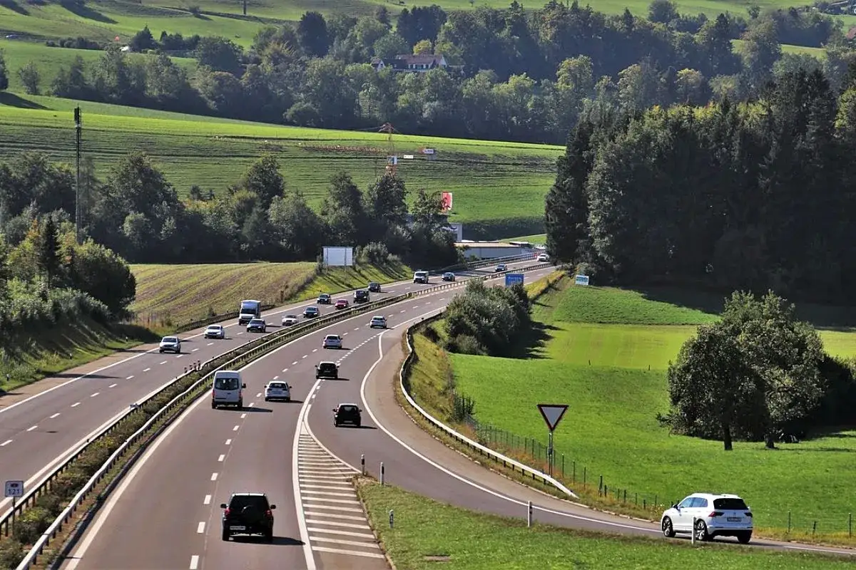 Coches circulan por una autopista en un paisaje verde. Para entrar en una autopista a qué velocidad debe circular es una pregunta clave para la seguridad.
