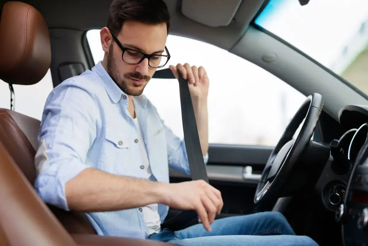 Hombre con gafas se abrocha el cintur&oacute;n de seguridad, listo para el pas conducci&oacute;n.