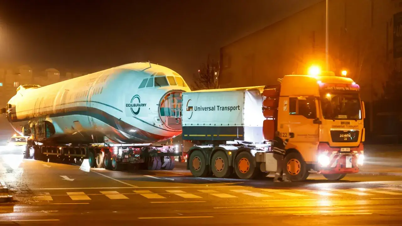 Un avi&oacute;n es transportado por camiones especiales de Universal Transport. La operaci&oacute;n nocturna muestra la magnitud de estos transportes especiales.