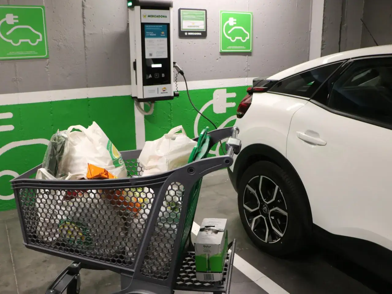 Coche el&eacute;ctrico cargando en Mercadona. &iquest;Cu&aacute;nto cuesta cargar un coche el&eacute;ctrico en Mercadona? Carrito lleno de la compra.