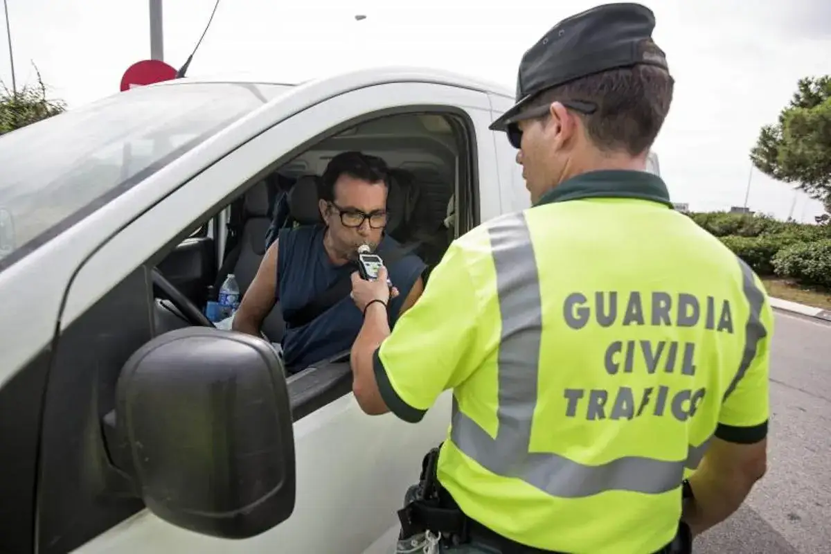 Agente de la Guardia Civil realiza prueba de alcoholemia a conductor. Se verifica la tasa de alcohol permitida para garantizar la seguridad vial.