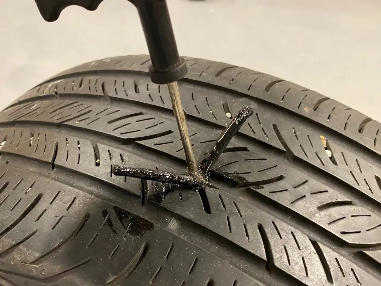 Herramienta insertada en un neum&aacute;tico para reparar pinchazo coche. El caucho negro sella la grieta.