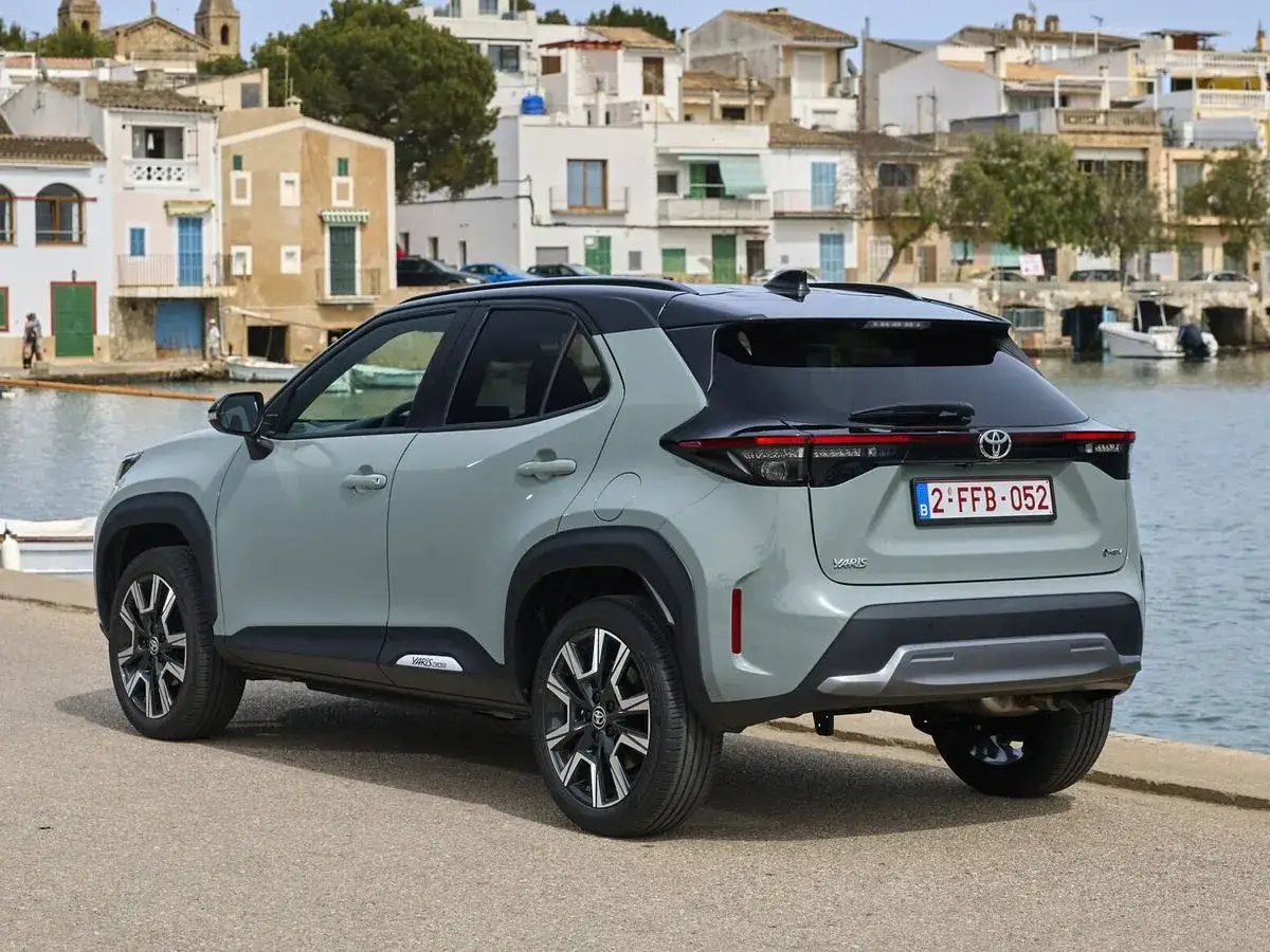 Coche gris con etiqueta eco en Cataluña, aparcado junto al mar en un pueblo costero.
