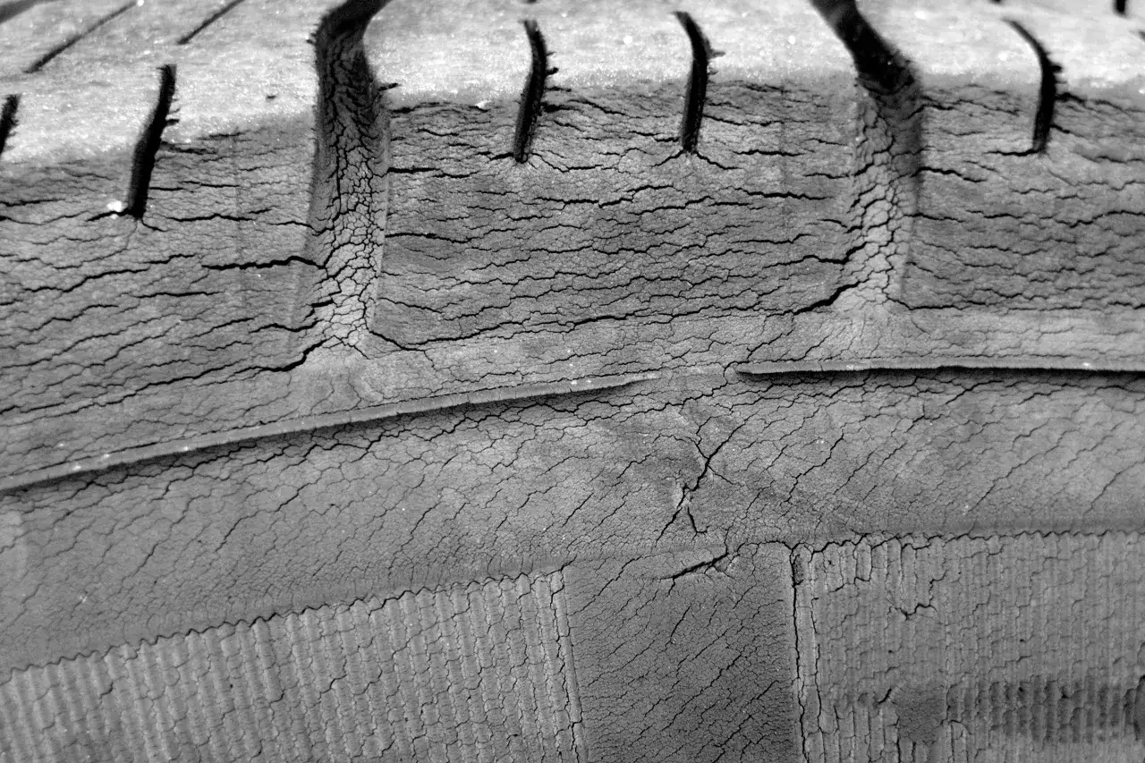 Primer plano de neumáticos cuarteados, mostrando el desgaste y las grietas profundas en la goma.
