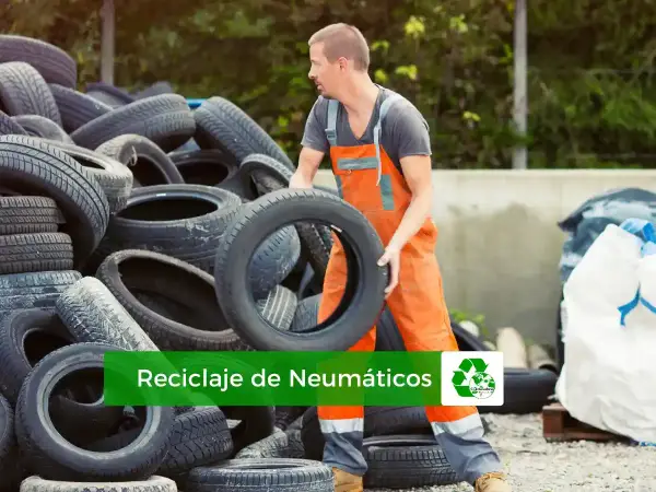 Trabajador gestionando el reciclaje de neumáticos. Montañas de llantas usadas esperan ser procesadas para un futuro más verde.