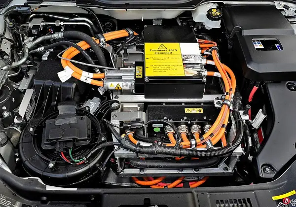Vista detallada de las partes de un coche eléctrico, mostrando cables naranjas de alta tensión, componentes electrónicos y un ventilador.